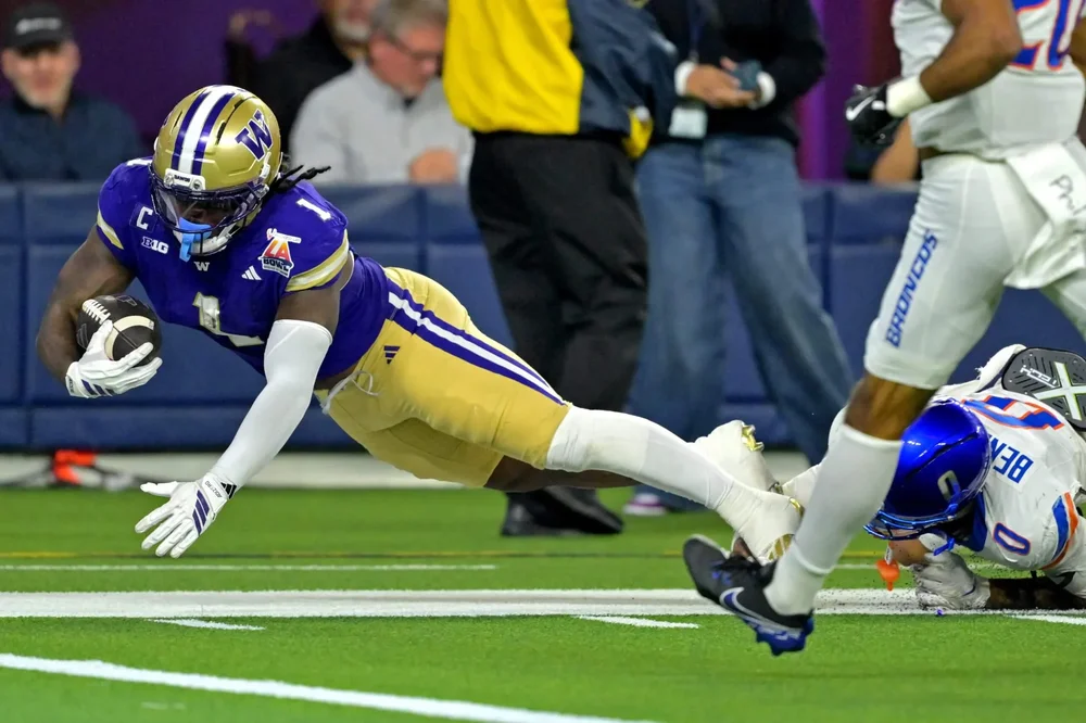 Jonah Coleman, midair and about to land on his stomach, catches a pass for the Washington Huskies.